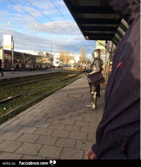 Uomo vestito da cavaliere in armatura alla fermata del treno