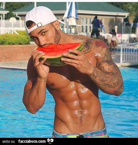 Ragazzo figo e muscoloso che mangia una fetta di anguria a bordo piscina