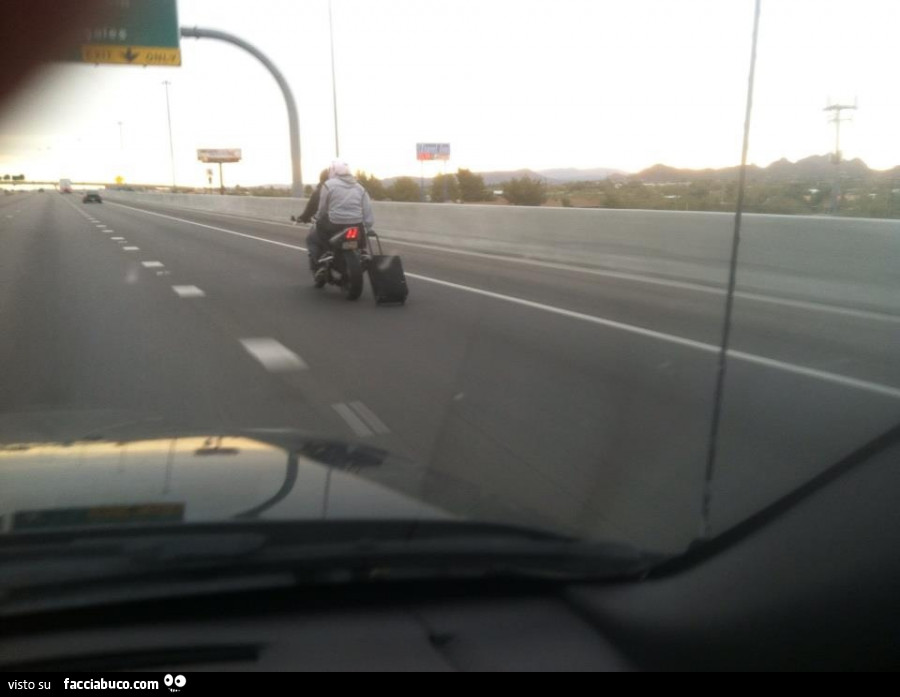 In moto in autostrada trascinando il trolley